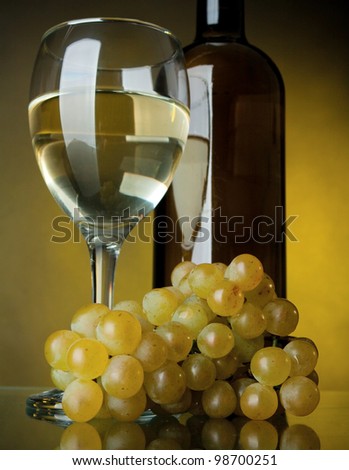 A glass of wine, bottle and grapes on a yellow background