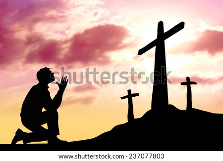 Silhouette of man praying to a cross with heavenly cloudscape sunset concept for religion