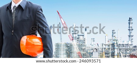 engineer orange helmet for workers security with large oil refinery background