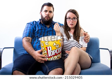 Couple watching TV on the couch and eating pop corn