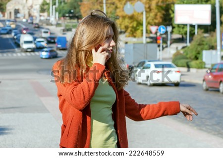 Young girl trying to stop the car on the road and talking on the phone