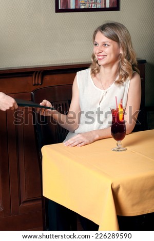 The girl takes her hand menu in the cafe and smiling