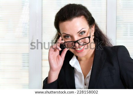 Beautiful girl in business attire looking over his glasses and laughs