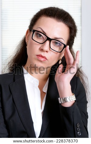 Woman leader in black business suit holds glasses on her face
