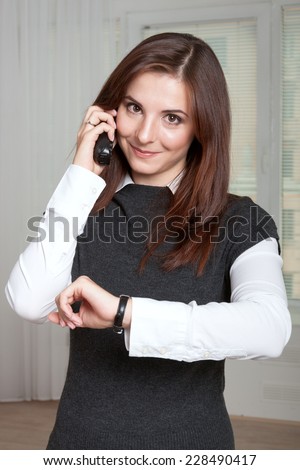 The girl speaks by phone and looks at her watch
