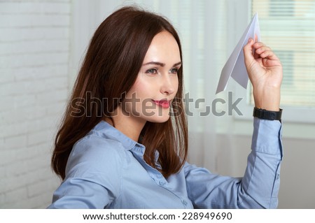 Woman sitting at a desk in an office and throwing a paper plane