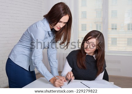 Couple of girls in formal clothes signing business documents and looking at each other