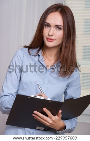 Woman in formal attire opened the folder for documents and writes it