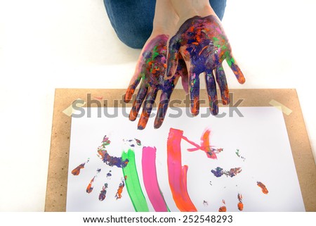 Girl shows hands in the paint against a sheet of paper