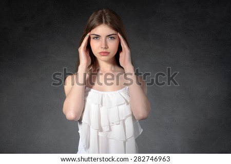 Concept human emotions. Girl shows that she had a headache against a dark background