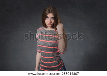 Anger, force, aggression concept. A woman shows a fist against a dark background