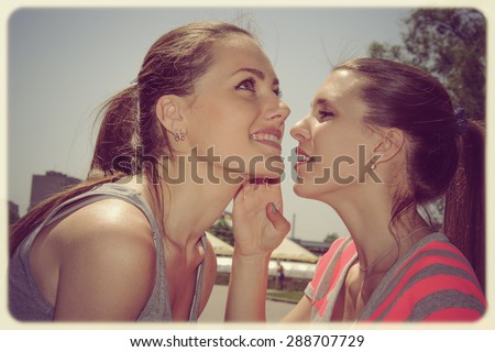 One girl tells another secret whisper in her ear