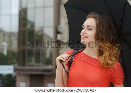 Independence, confidence, elegance concept. Slim girl walking down the street of the city under an umbrella