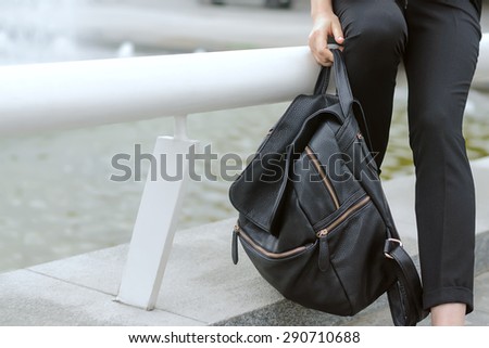Fatigue, tiredness concept. A girl holding a heavy backpack in her hand