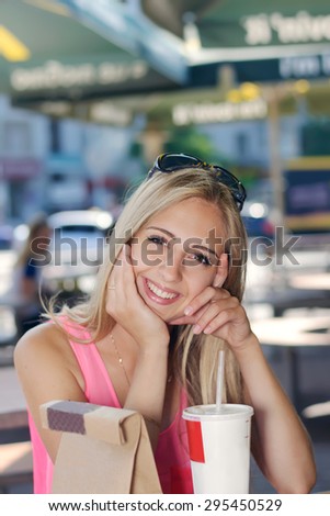 Girl sitting in an outdoor cafe, Fast food and smiling against the dark background