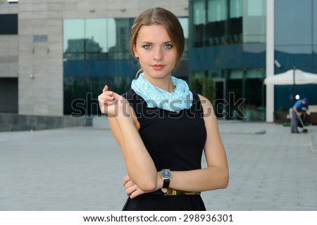 Business woman in formal attire is standing against the facade of a modern building