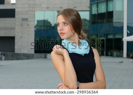 Business woman in formal attire is standing against a background of modern building facades