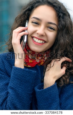 Woman speaks on the phone walking on a city street in a blue coat