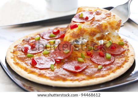 Slice of pepperoni pizza being removed Isolated over white