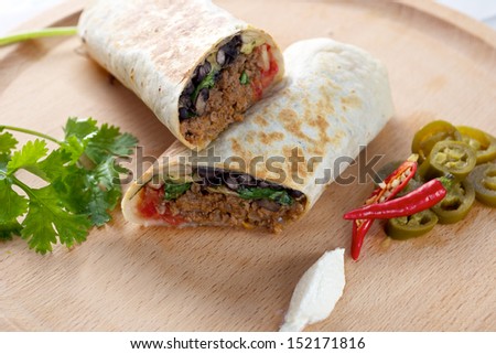 Beef Burrito on wooden board with red chillies peppers