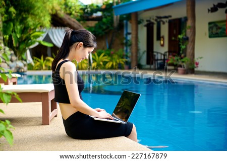 Girl with Laptop by the pool, working on vacation with mobility concept