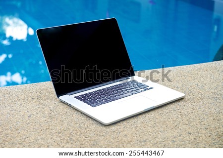 Laptop by the pool, working on vacation with mobility concept