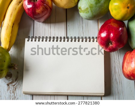 notebook for recipes with fresh fruits on wooden background