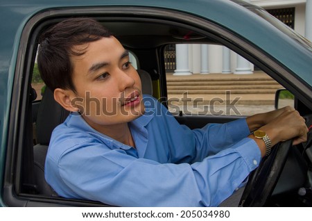 a man lean out from his car to see what happen in front of his car.Driving a car,you may face with traffic jam,people or animals cross the road suddenly or accident which can interrupt your driving.
