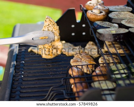 Barbecued chicken being flipped on an outdoor grill