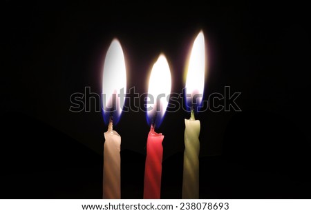 Three color candles with flame at night closeup