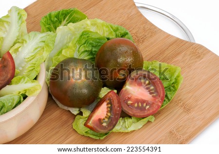 Black tomatoes , whole and cut on a chopping board.