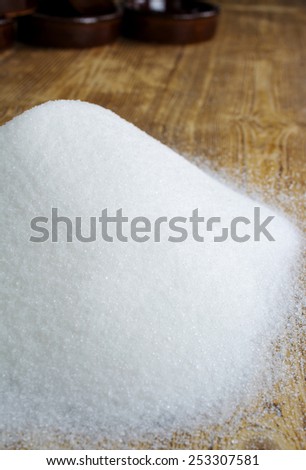 Vertical,Selective focus of a pile of sugar poured on an old farmhouse table, with room for text.