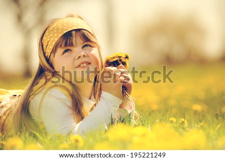 little girl enjoying the sunny spring day in fields flowers. vintage-look / girl in field of flowers