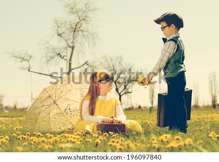 little boy courting a girl of the park in a flower meadow.vintage-look / little romance
