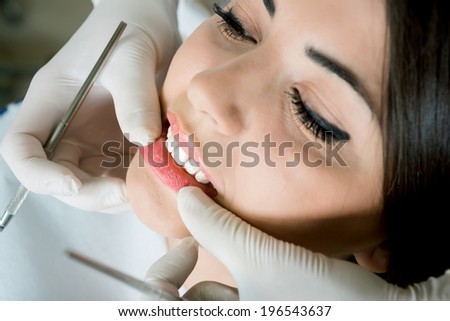 young women to the dentist in the dental chair sits next to a doctor to do the dentist to see if his teeth were okay/girl at the dentist