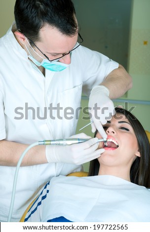 young women to the dentist in the dental chair sits next to a doctor to do the dentist to see if his teeth were okay / girl at the dentist