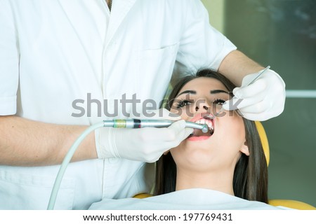 young women to the dentist in the dental chair sits next to a doctor to do the dentist to see if his teeth were okay/ girl at the dentist