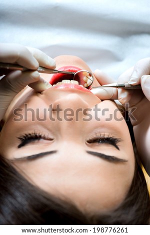 young women to the dentist in the dental chair sits next to a doctor to do the dentist to see if his teeth were okay / girl at the dentist