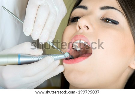 young women to the dentist in the dental chair sits next to a doctor to do the dentist to see if his teeth were okay /girl at the dentist