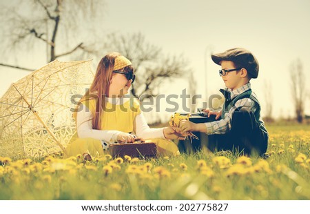 little boy courting a girl of the park in a flower meadow.vintage-look/little boy courting a girl