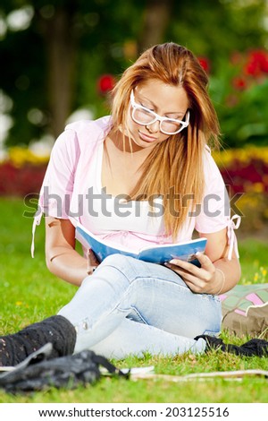 young high school student or college girl learn and sit in the park on the green grass/young high school studen