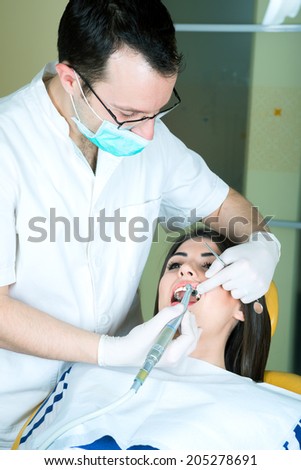 young women to the dentist in the dental chair sits next to a doctor to do the dentist to see if his teeth were okay/young women to the dentist