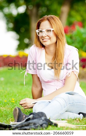 young high school student or college girl learn and sit in the park on the green grass/young college or high school student