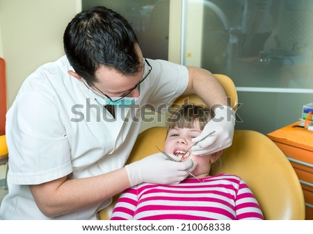 little girl to the dentist in the dental chair sits next to a doctor to do the dentist to see if his teeth were okay/little girl to the dentist in the dental chair