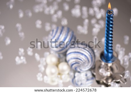 silver candlestick with one blue candle and glass balls stands next to a multitude of crystal stones on the mirror/ one blue candle and glass balls