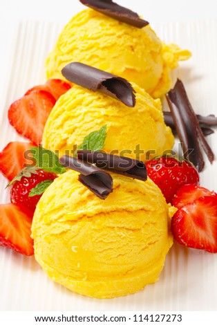 Three scoops of ice cream garnished with chocolate curls and strawberries