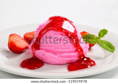 Scoop of pink ice cream with strawberry sauce