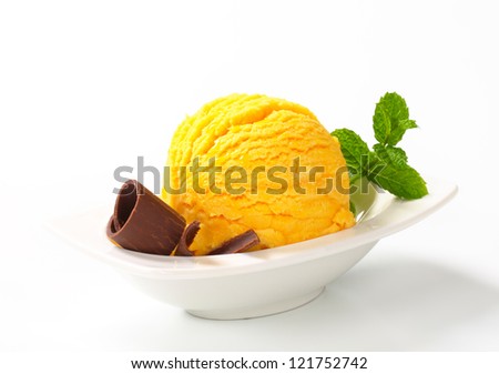 Scoop of yellow ice cream garnished with chocolate curl