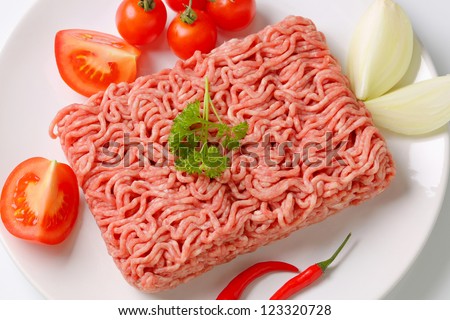 Raw ground pork and vegetables on plate