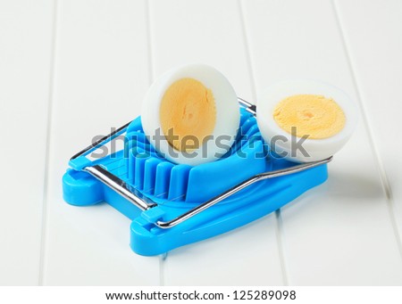 Boiled egg cut in halves and an egg slicer